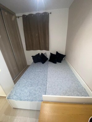 Cozy retreat with a single bed, wooden wardrobe, and tiled floor.
