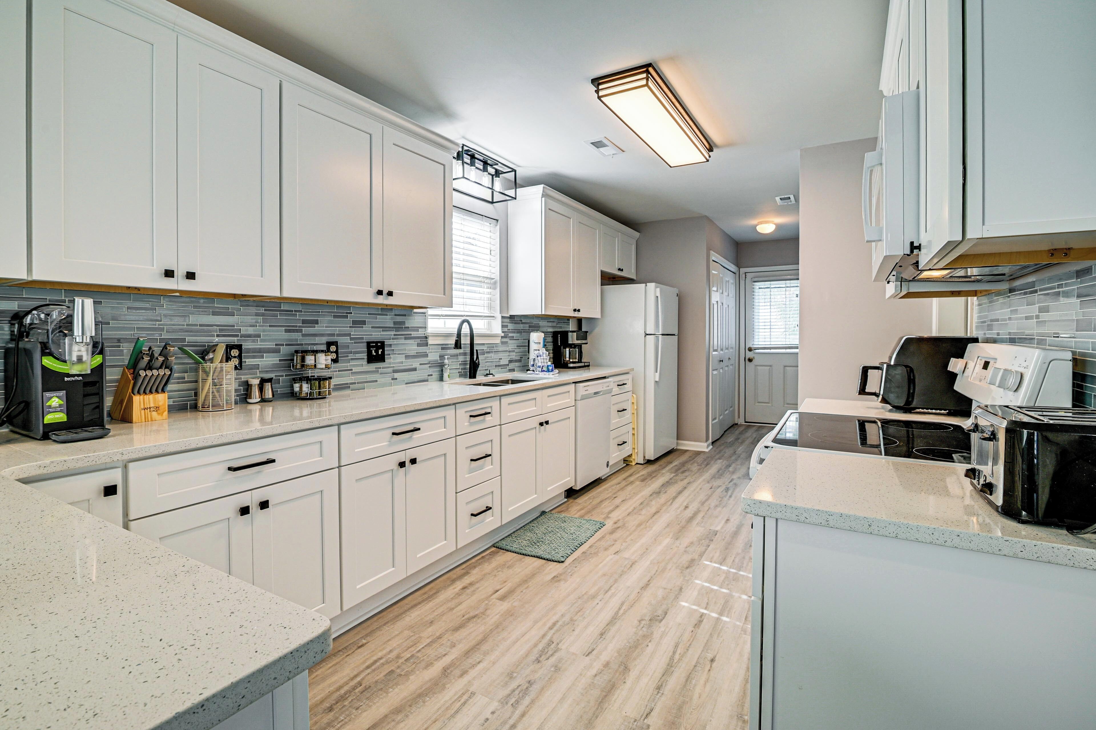 A modern kitchen with white cabinets, a granite countertop, and a built-in oven.