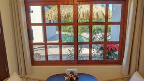 Una habitación con un amplio ventanal de arco, una mesa redonda con dos sillas y una lámpara colgante.