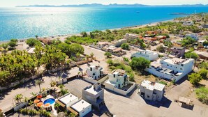 Vista aérea de un pueblo costero con edificios, una playa y un mar azul cristalino.
