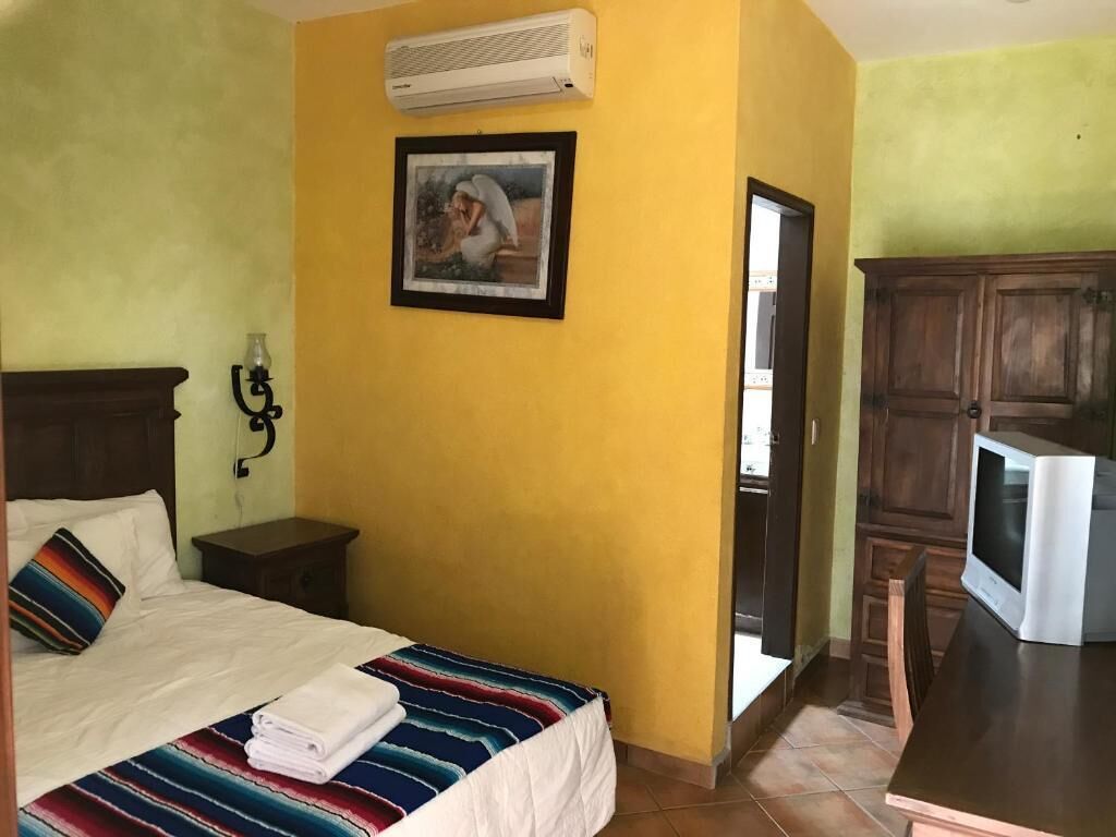 Een hotelkamer met een bed, een televisie, een kast en een foto aan de muur.