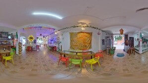 Une pièce spacieuse dotée d’un sol carrelé, d’un espace salon central avec des fauteuils et d’une grande tapisserie accrochée au mur.