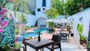 Une terrasse extérieure avec une piscine, des meubles en osier et des plantes en pot.