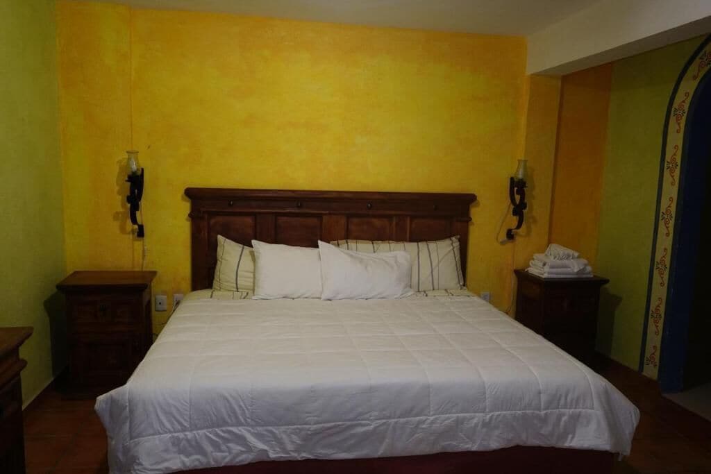 Un dormitorio con una cama grande, cabecera de madera y dos mesitas de noche.