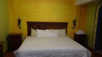 Un dormitorio con una cama grande, cabecera de madera y dos mesitas de noche.