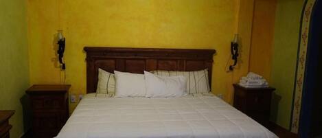 A bedroom with a large bed, wooden headboard, and two bedside tables.