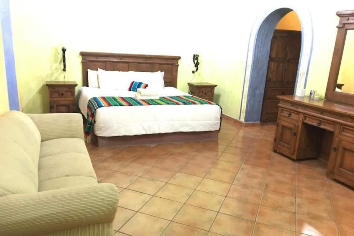 Quarto com cama, mesa de cabeceira, cômoda e cadeira.