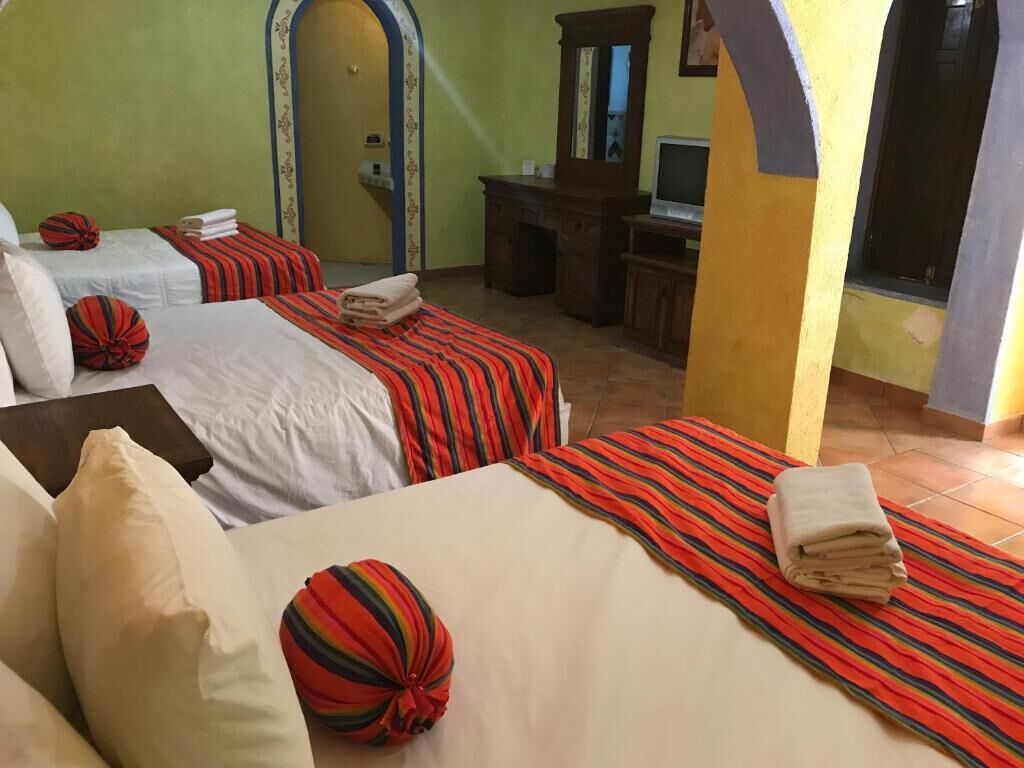 Une chambre d’hôtel avec deux lits, chacun doté de draps et d’oreillers à rayures. On y trouve un bureau avec un ordinateur et un miroir.