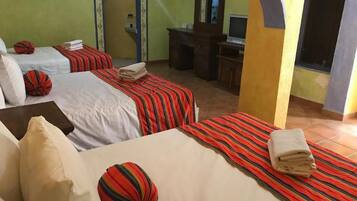 Une chambre d’hôtel avec deux lits, chacun doté de draps et d’oreillers à rayures. On y trouve un bureau avec un ordinateur et un miroir.