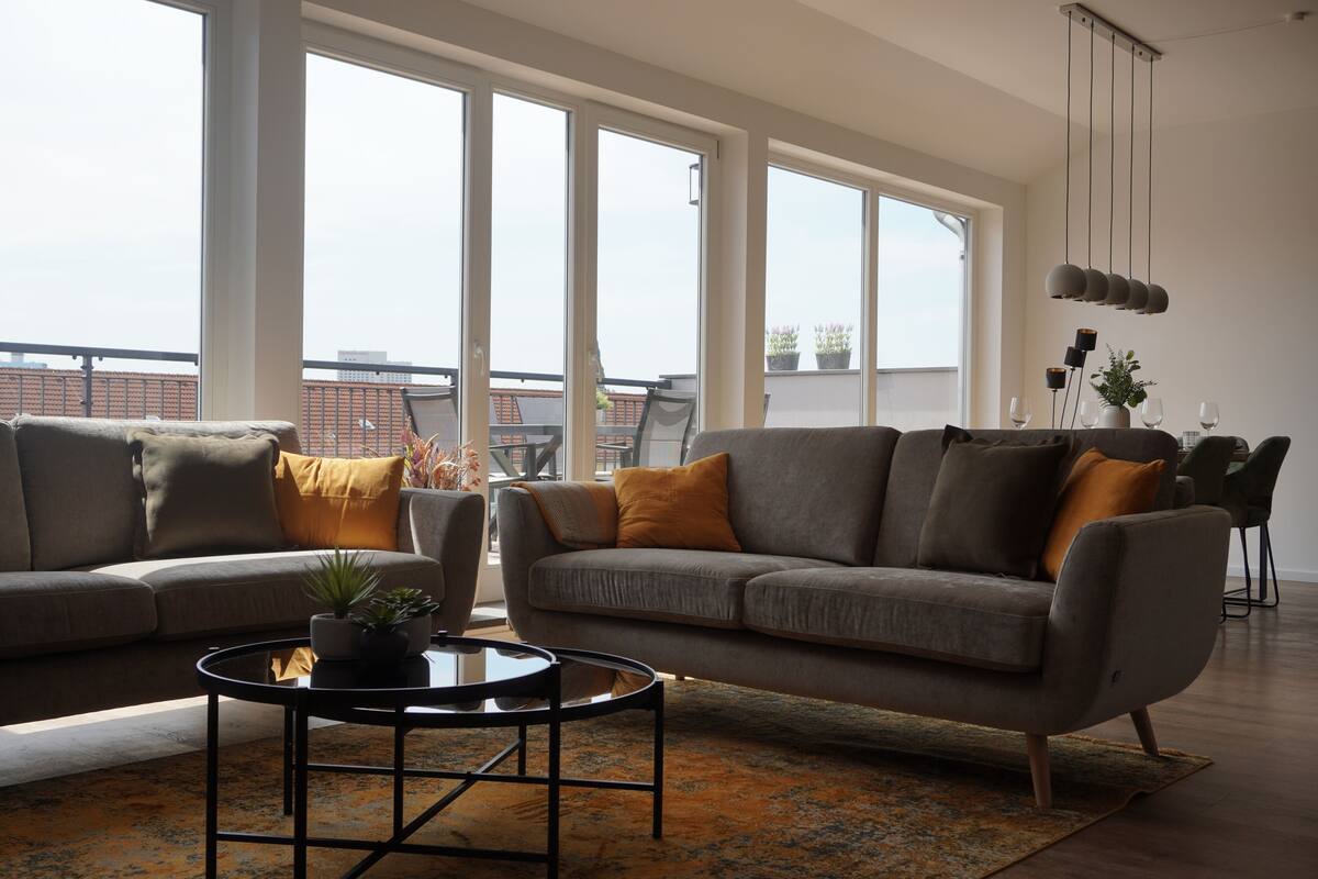 Ein modernes Wohnzimmer mit zwei Sofas, einem Couchtisch und großen Fenstern mit Blick auf die Stadt.