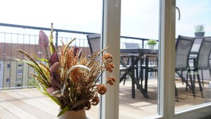 A balcony with a potted plant, a dining table, and chairs. - Sleepwell Apartment - Ehrensteinsuite (Leipzig)