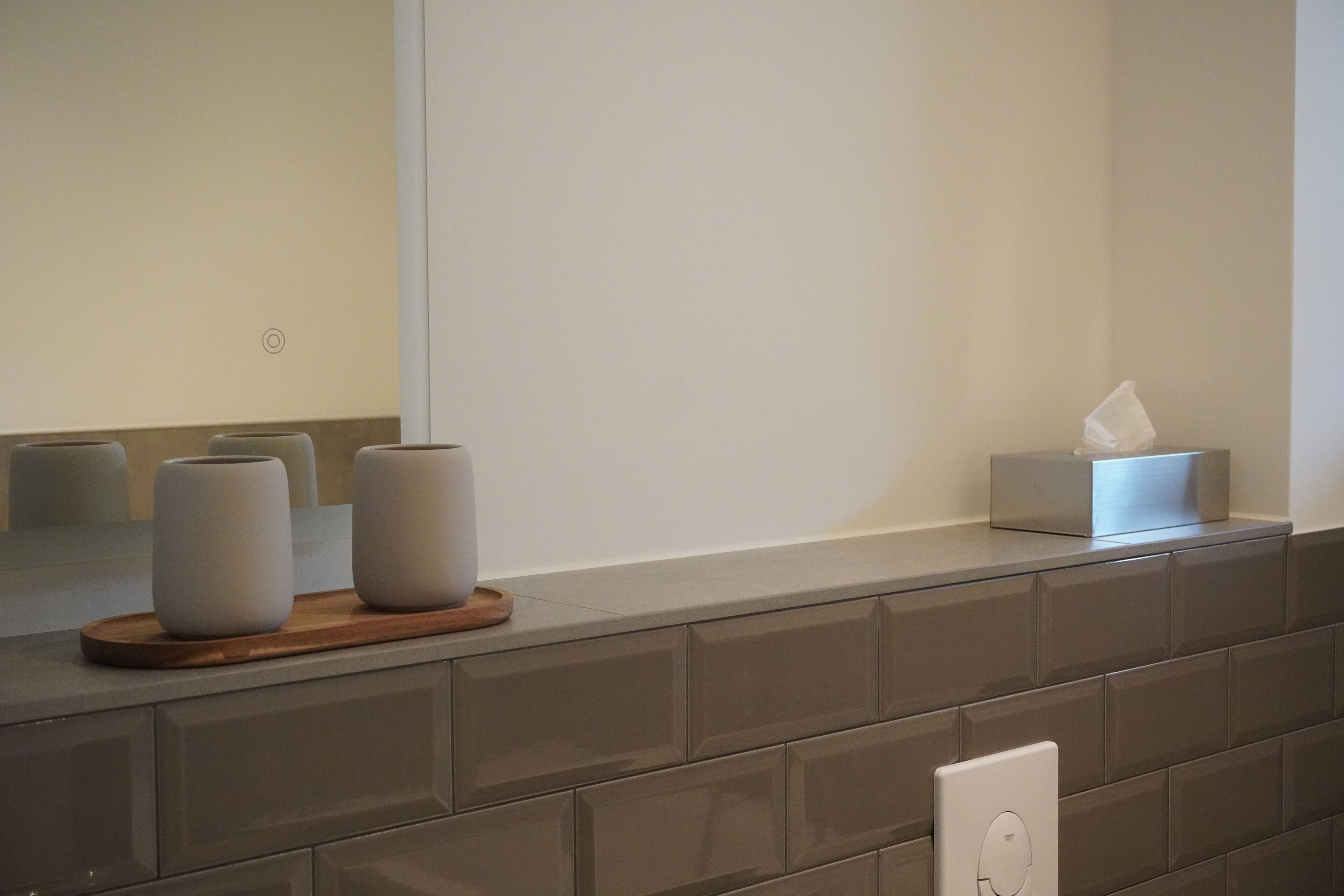 Una encimera de baño con dos recipientes blancos cilíndricos, una caja de pañuelos y un dispensador de jabón.