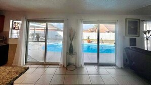 A living room with a view of a swimming pool through glass doors. - Casa Santa Clara with Swimming Pool near Golf Country Clubs (Brownsville)