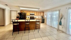 A kitchen with a central island, bar stools, a microwave, and a coffee maker. - Casa Santa Clara with Swimming Pool near Golf Country Clubs (Brownsville)