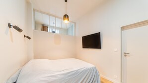 A bedroom with a bed, a TV mounted on the wall, and a door.