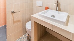 A bathroom with a white sink, a mirror, and a toilet.