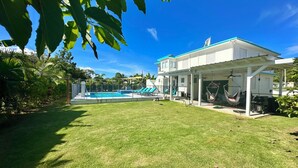 Una casa con piscina, un porche cubierto y una hamaca.