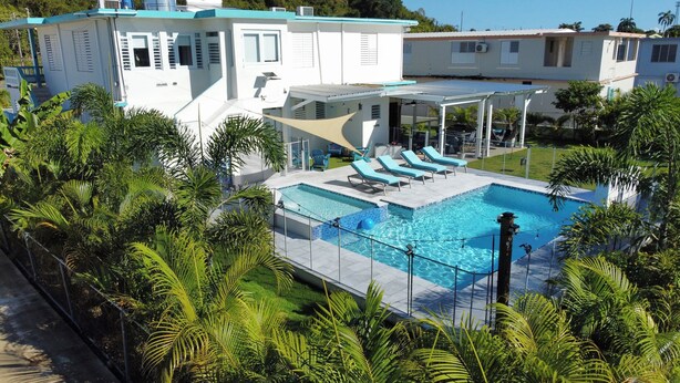 Un edificio moderno con zona de piscina, sillones de descanso y un área de estar cubierta.