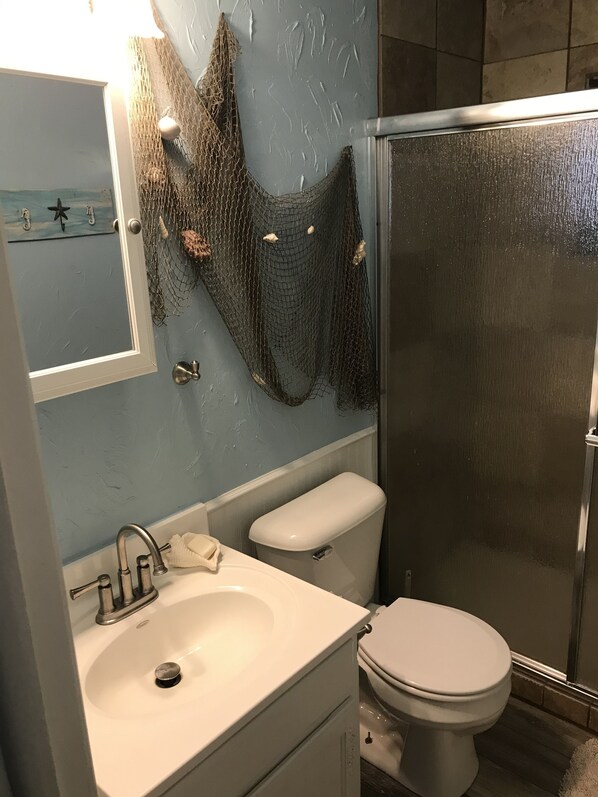 Un baño con lavamanos blanco, inodoro y cabina de ducha.