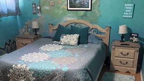 A bedroom with a bed, two nightstands, a wooden floor, a mural on the wall, and a small rug. - Farm stay close to Colorado Springs! Pine trees, fresh air, goats and chickens! (Calhan)