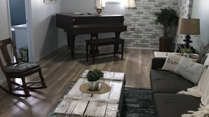 A living room with a piano, a sofa, a coffee table, and a lamp. - Farm stay close to Colorado Springs! Pine trees, fresh air, goats and chickens! (Calhan)