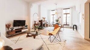 A spacious living room with a television, a glass coffee table, and a comfortable chair. - Traditional chic high ceilings apt w Aircos/Garage (Antwerpen)