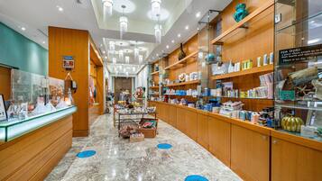 A well-lit spa area with wooden shelves stocked with various spa products, a reception desk, and a marble floor.