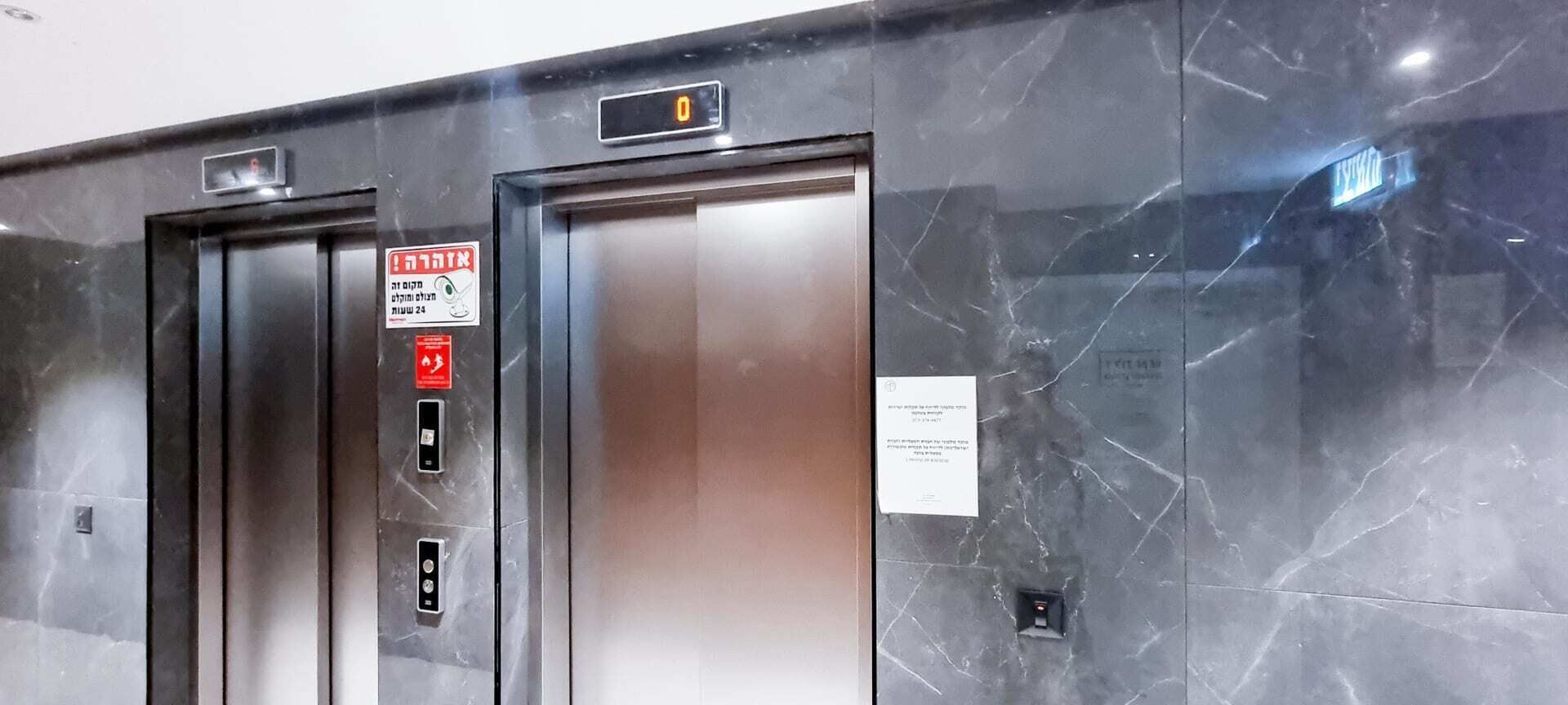 An elevator with a digital display, emergency instructions, and a marble wall.