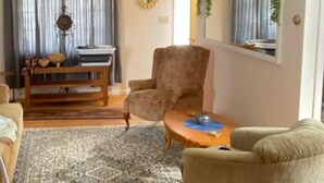 Ein Wohnzimmer mit Teppich mit Muster, einem Holztisch und zwei Sesseln.