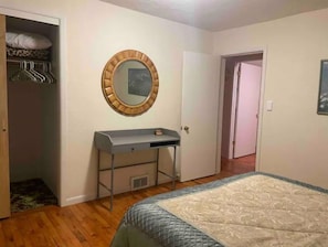 Une chambre à coucher avec un lit, une table de chevet, un miroir, une armoire et une porte.