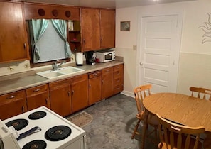 Une cuisine de taille réduite, avec des meubles en bois, une cuisinière blanche, un évier et un four à micro-ondes.