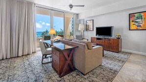 A modern living room with a sofa, TV, and a desk. - Palm Beach Singer Island Resort & Spa Luxury Suites 1/1 Resort View (Riviera Beach)