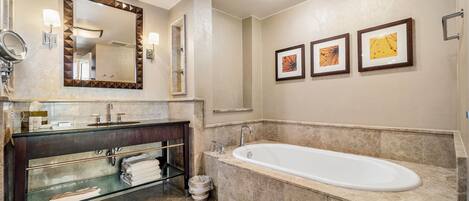 A modern bathroom with a large bathtub, a vanity with a mirror, and three framed pictures on the wall.