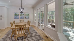 A dining area with a wooden table and chairs, a hanging light fixture, and large windows overlooking a deck. - Luxury Lakefront Retreat w/ Deck & Patio! (Edgemont)