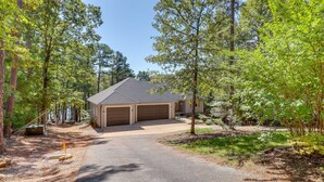 A two-story house with a garage, surrounded by a forested area. - Luxury Lakefront Retreat w/ Deck & Patio! (Edgemont)