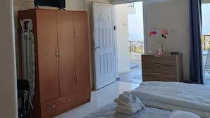 A hotel room with a bed, a wardrobe, a television, a balcony with a view, and a door leading outside. - Studio/scenic Views/pool/air Con/near Attractions (Pegeia)