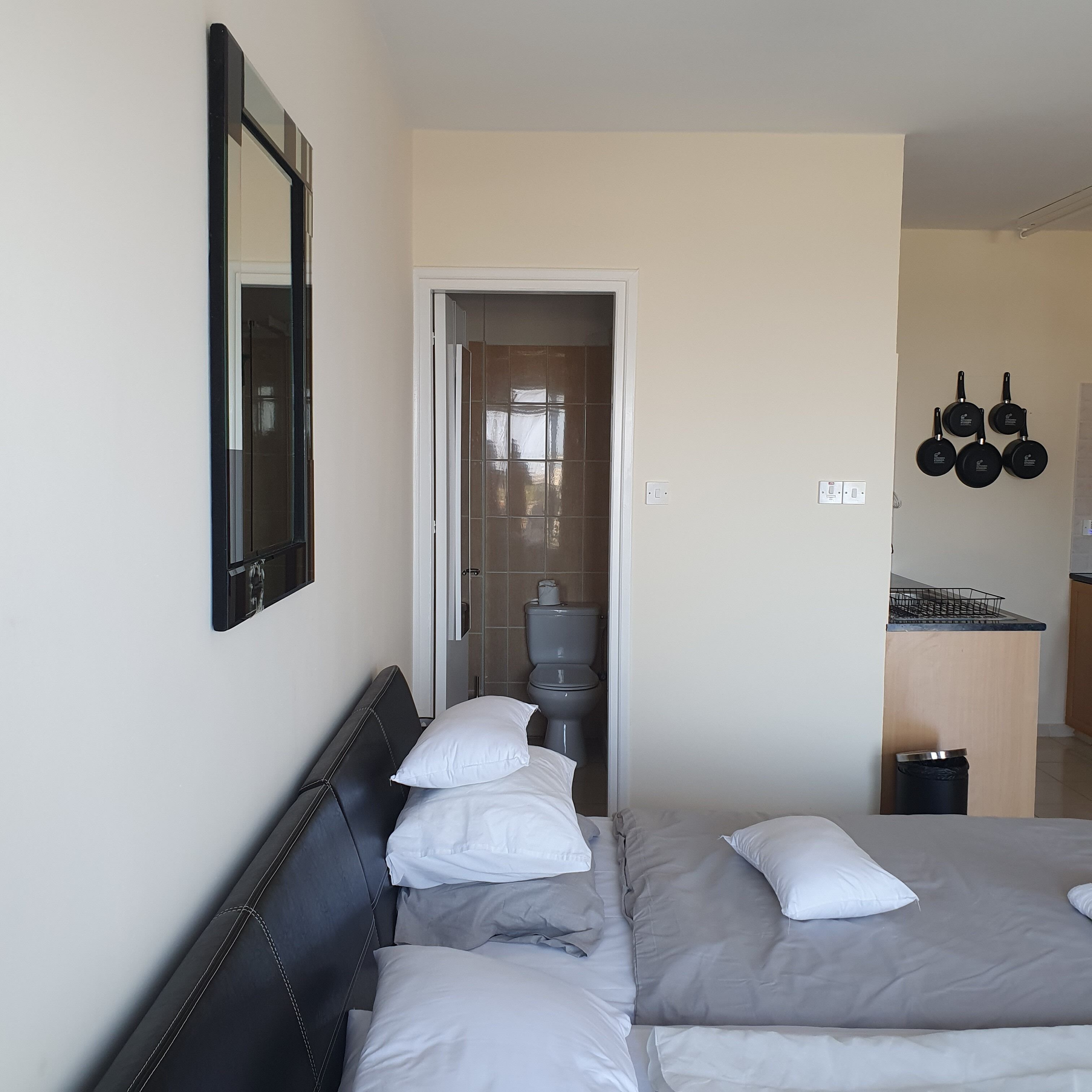 Ein Hotelzimmer mit Bett, Spiegel, Toilette und einer Küchenzeile.