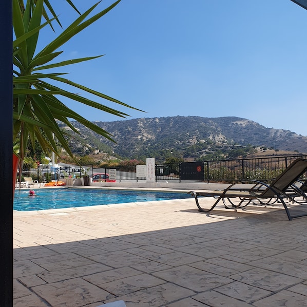 Un espace piscine comprenant des chaises longues, une piscine et une vue sur les montagnes en arrière-plan.