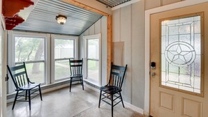 A room with a large window, a door with a stained glass design, and two wooden chairs. - Lake Brownwood Home w/ Private Boat Dock! (Brownwood)