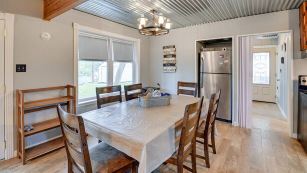 A dining area with a table, chairs, a chandelier, and a refrigerator. - Lake Brownwood Home w/ Private Boat Dock! (Brownwood)
