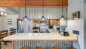 A kitchen with a large island, wooden cabinets, stainless steel appliances, and a clock on the wall. - Lake Brownwood Home w/ Private Boat Dock! (Brownwood)
