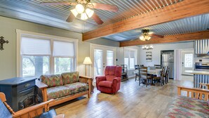 A spacious living room with a wooden ceiling, a red armchair, a patterned sofa, and a dining area with a table and chairs. - Lake Brownwood Home w/ Private Boat Dock! (Brownwood)