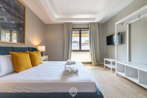 A hotel room with a bed, a TV, a painting, and a view of the outside. - Annina's Apartment - City Centre (Cagliari)