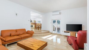 A modern living room with a leather sofa, a wooden coffee table, and a red massage chair. - Lovely home in Vodnjan (Vodnjan)