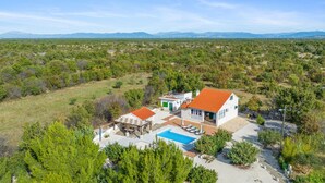 Una casa con piscina, patio y vistas del paisaje circundante.
