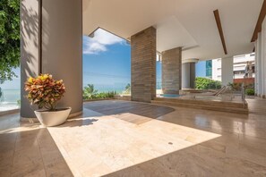 Enjoy the ocean view from this spacious area with a large potted plant and columns supporting the ceiling.