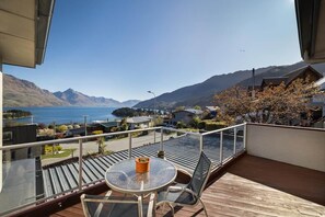 Ein Balkon mit Tisch und Stühlen, mit Blick auf einen See und Berge.