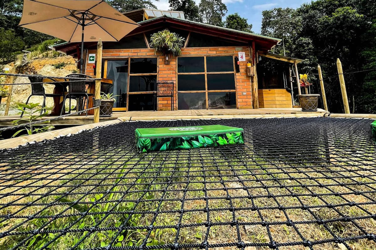 A rustic cabin with a large patio area, outdoor seating, and a view of the sky.