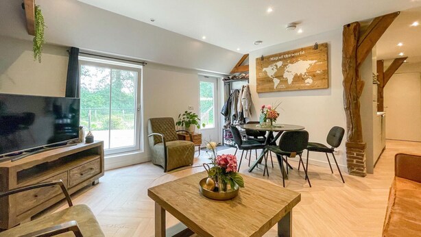 A modern living room with a television, a dining area with a table and chairs, and a large world map on the wall. - Lovely home in Putten with kitchen (Putten)