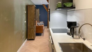 A modern kitchen with a stainless steel sink, a coffee maker, and a kettle. There is a wooden cabinet and a chair with a patterned cushion. - Lovely home in Putten with kitchen (Putten)
